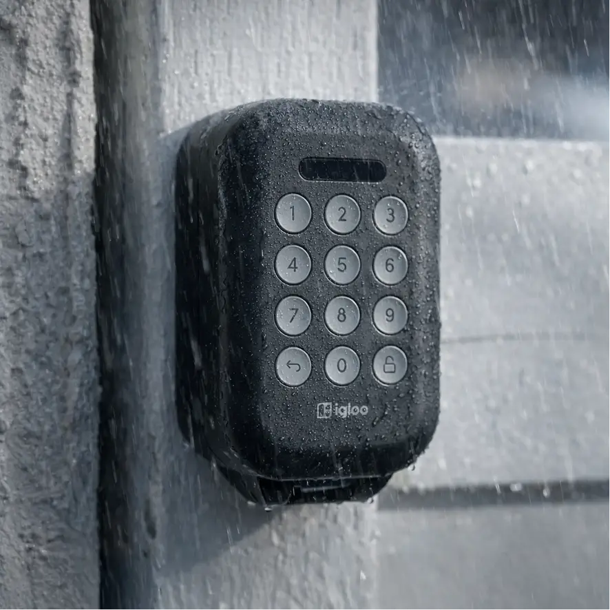 An igloo Lockbox mounted to a concrete wall in heavy rain, water running down the keypad