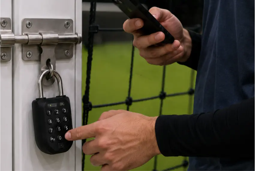A player unlocking an igloo smart padlock on the access gate to a self-serve futsal court