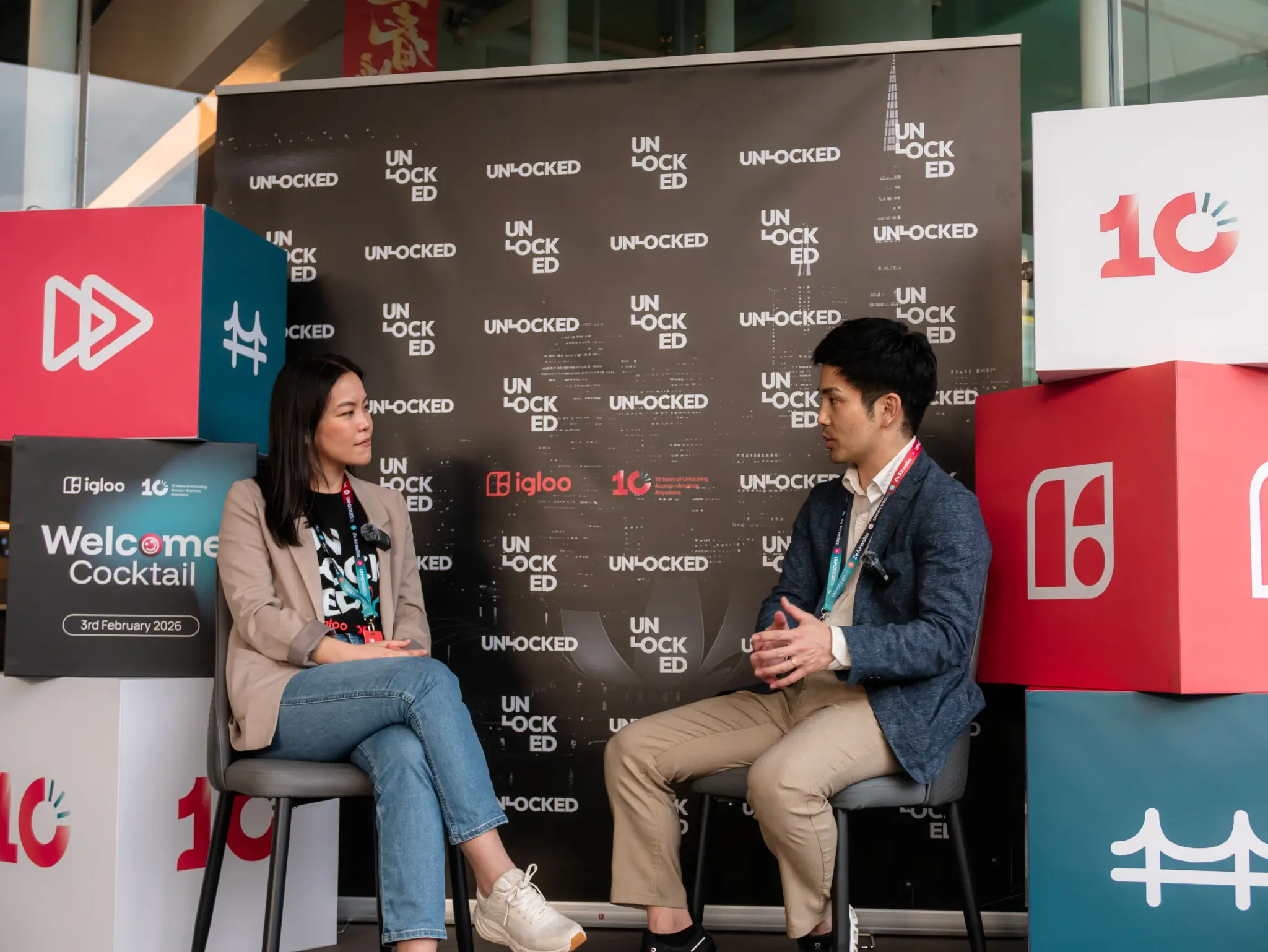 Seated interview with two guests in front of the UNLOCKED26 media wall