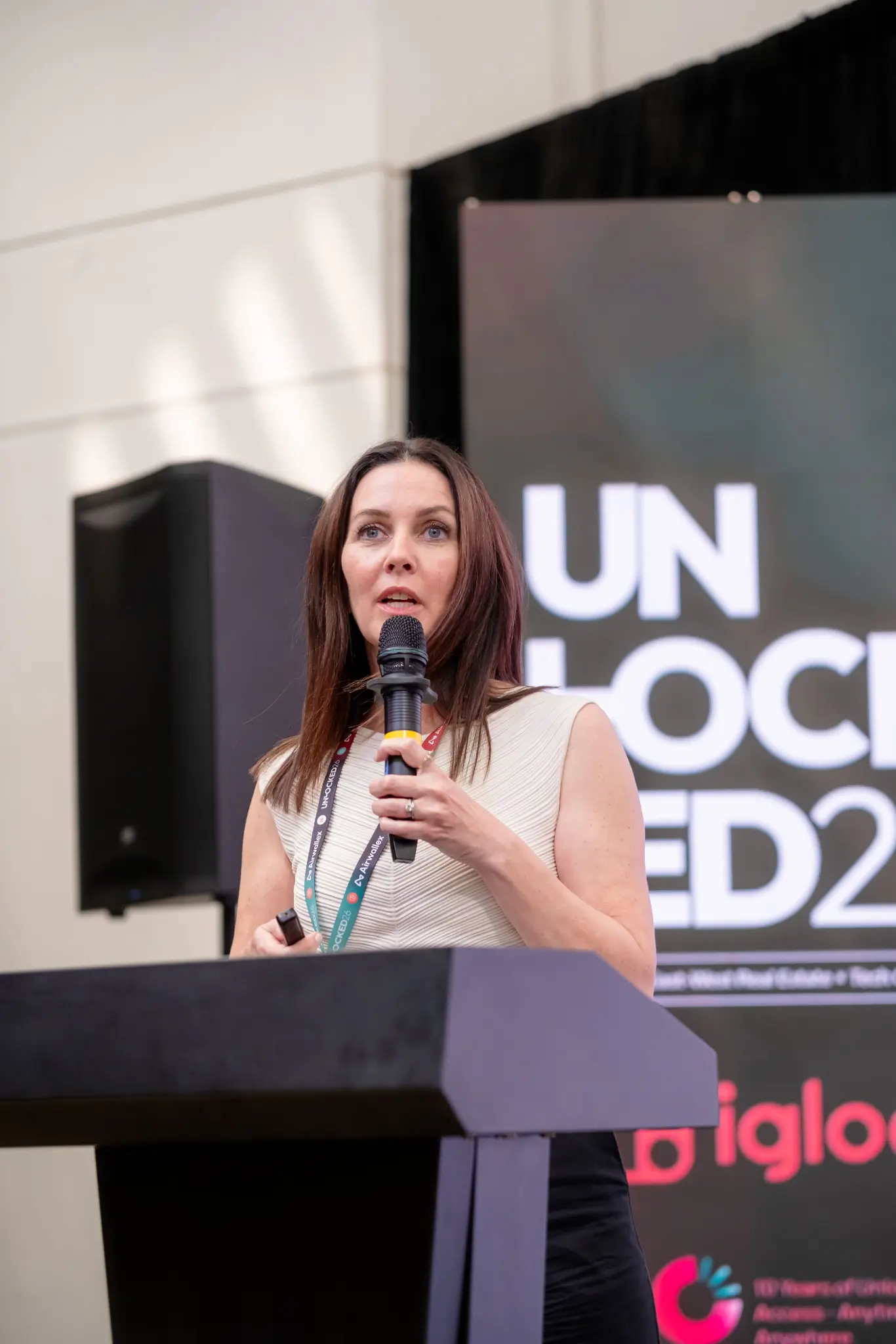 Speaker addressing the room from the podium on the UNLOCKED26 main stage