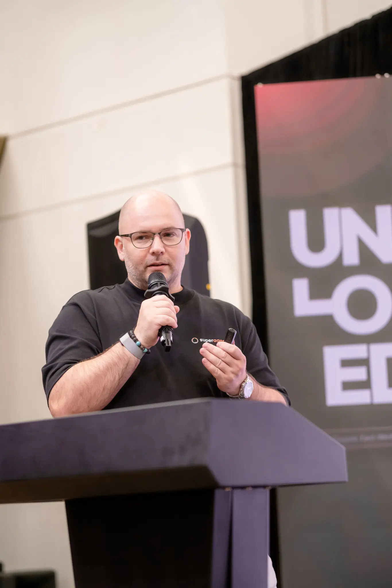 Speaker at the podium in front of the UNLOCKED26 backdrop