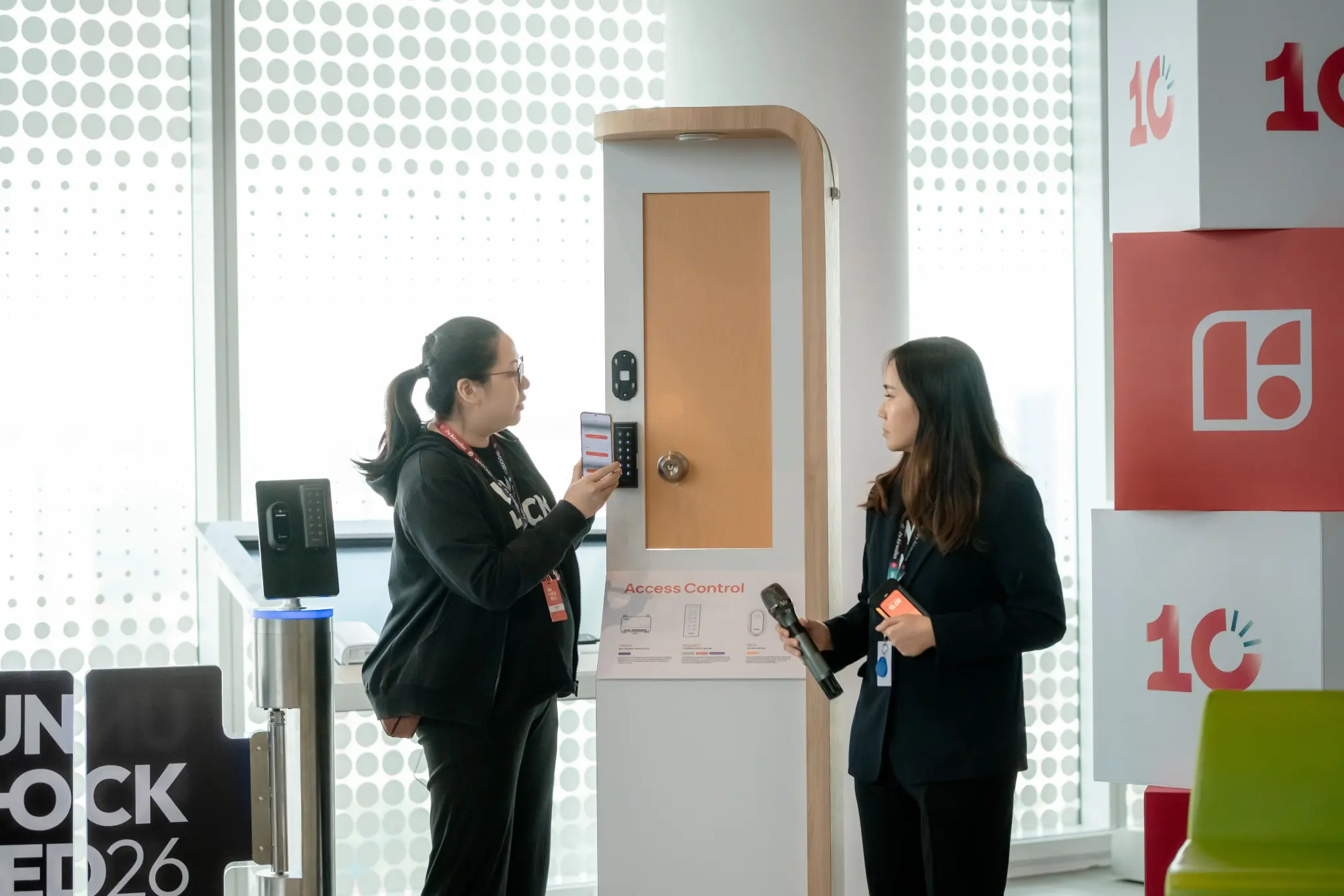 Two attendees trying a smart lock on a door display at the UNLOCKED26 demo area