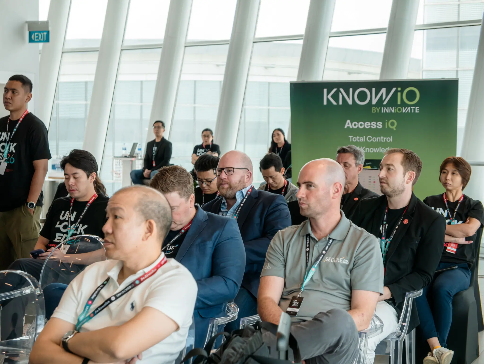 Attendees seated in the audience beside a KNOWiO Access IQ banner at UNLOCKED26