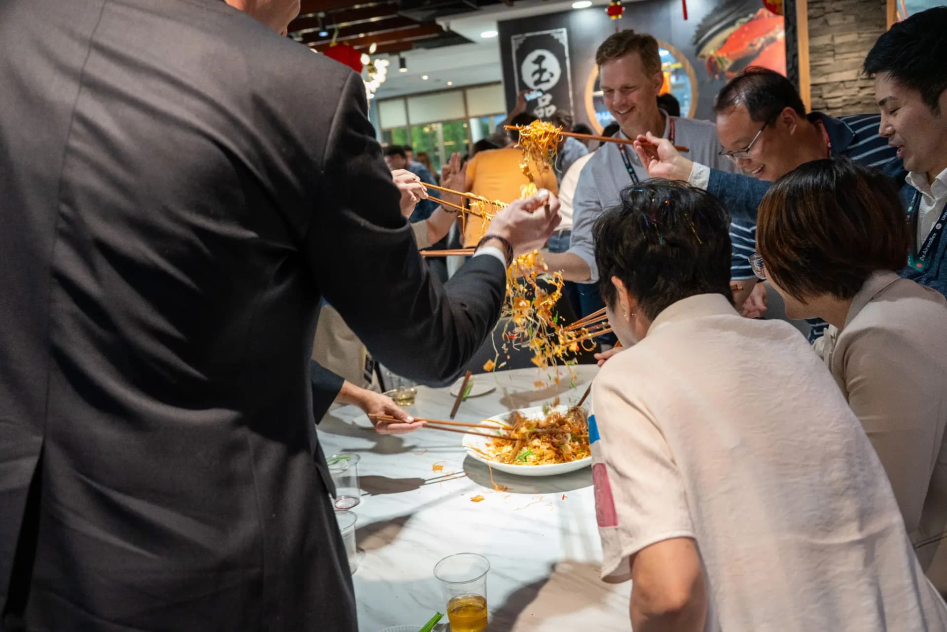 Guests tossing yusheng together at the UNLOCKED26 networking dinner