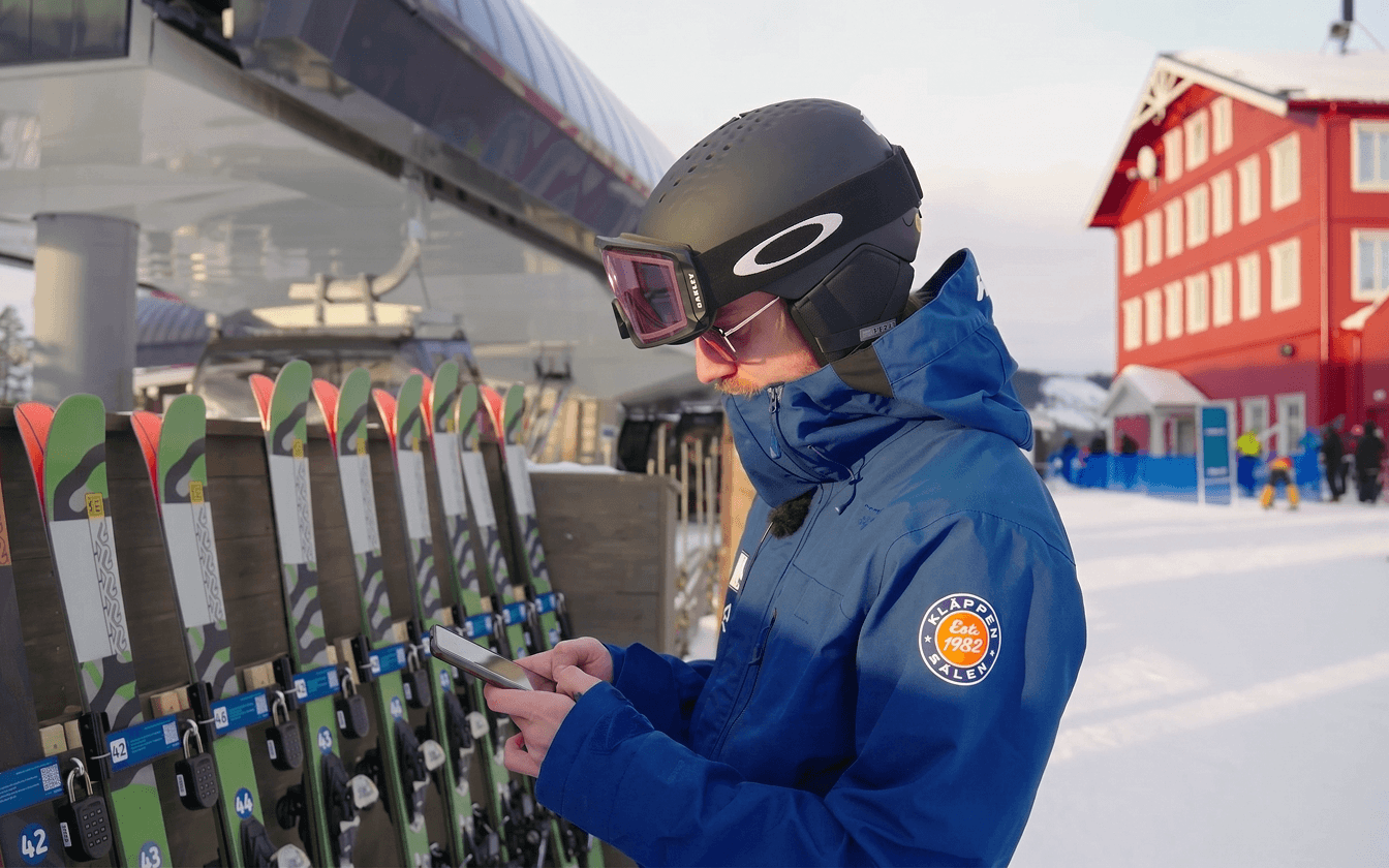 Skier unlocking a pair of skis from a self-service rental rack with their phone