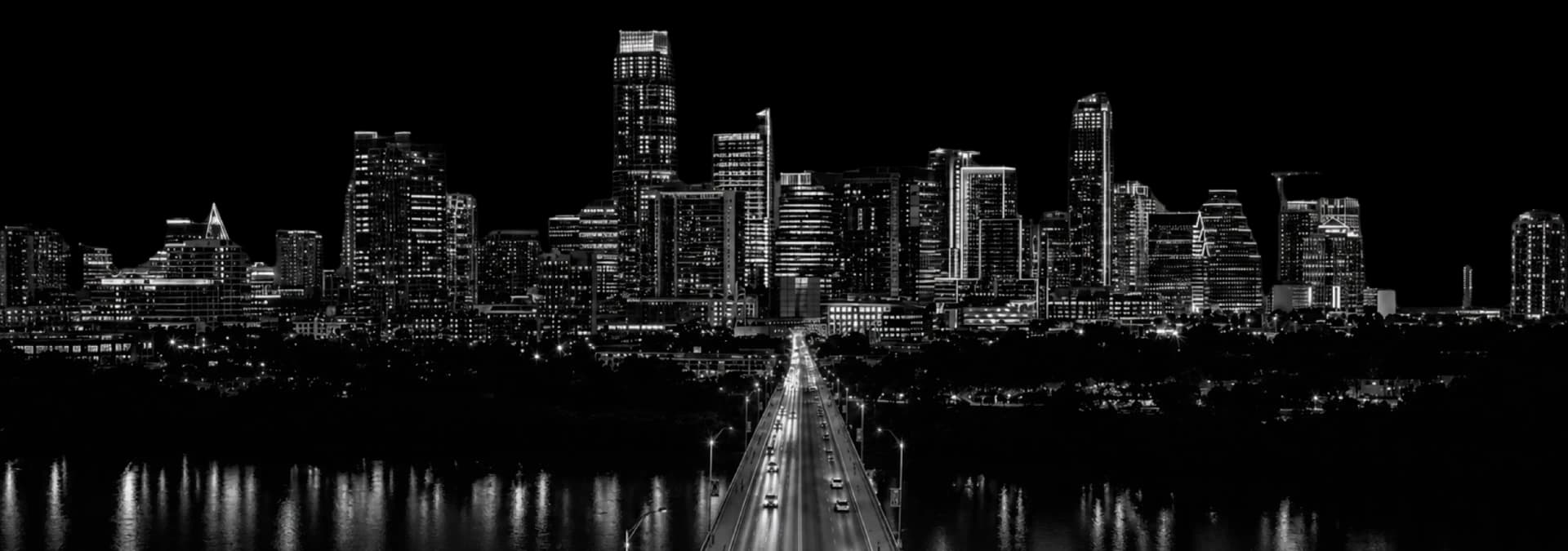Black-and-white Austin skyline at night, Congress Avenue bridge leading into downtown over Lady Bird Lake