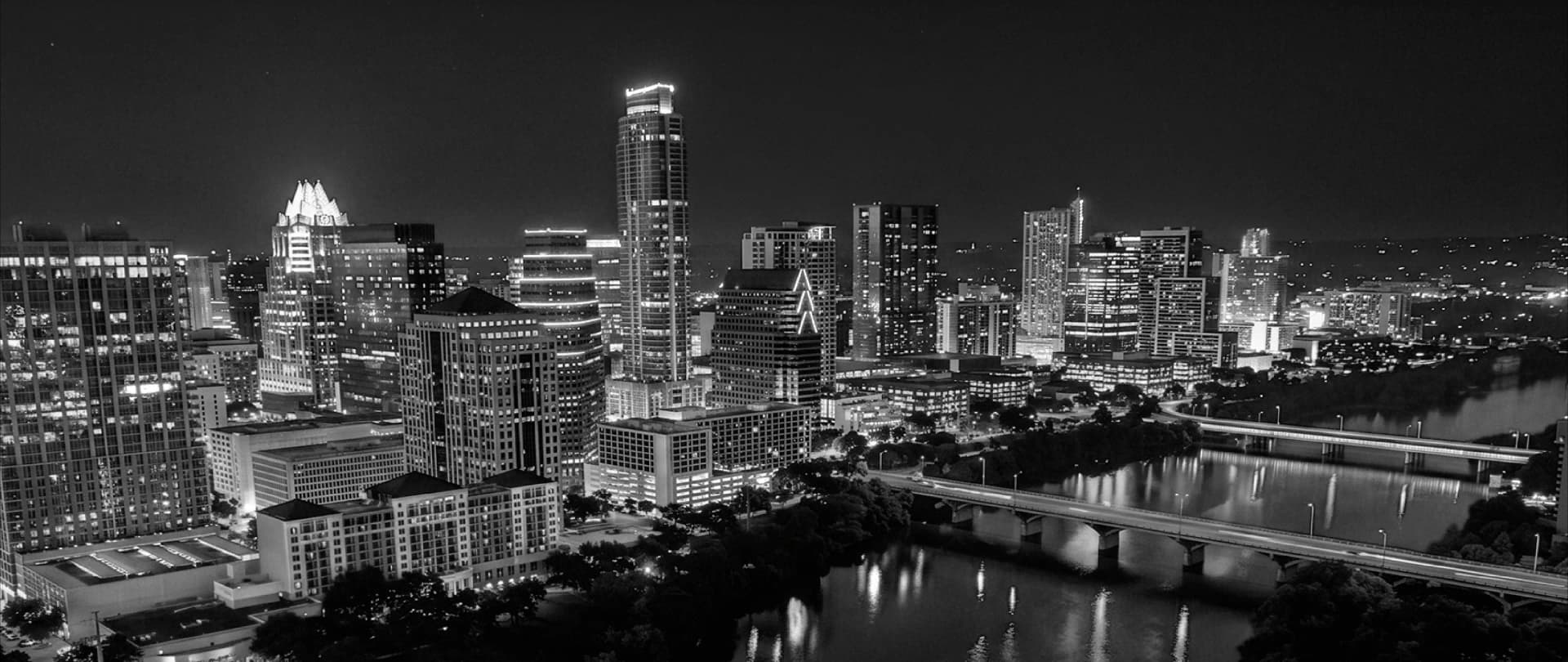 Black-and-white Austin skyline at night, downtown towers above Lady Bird Lake