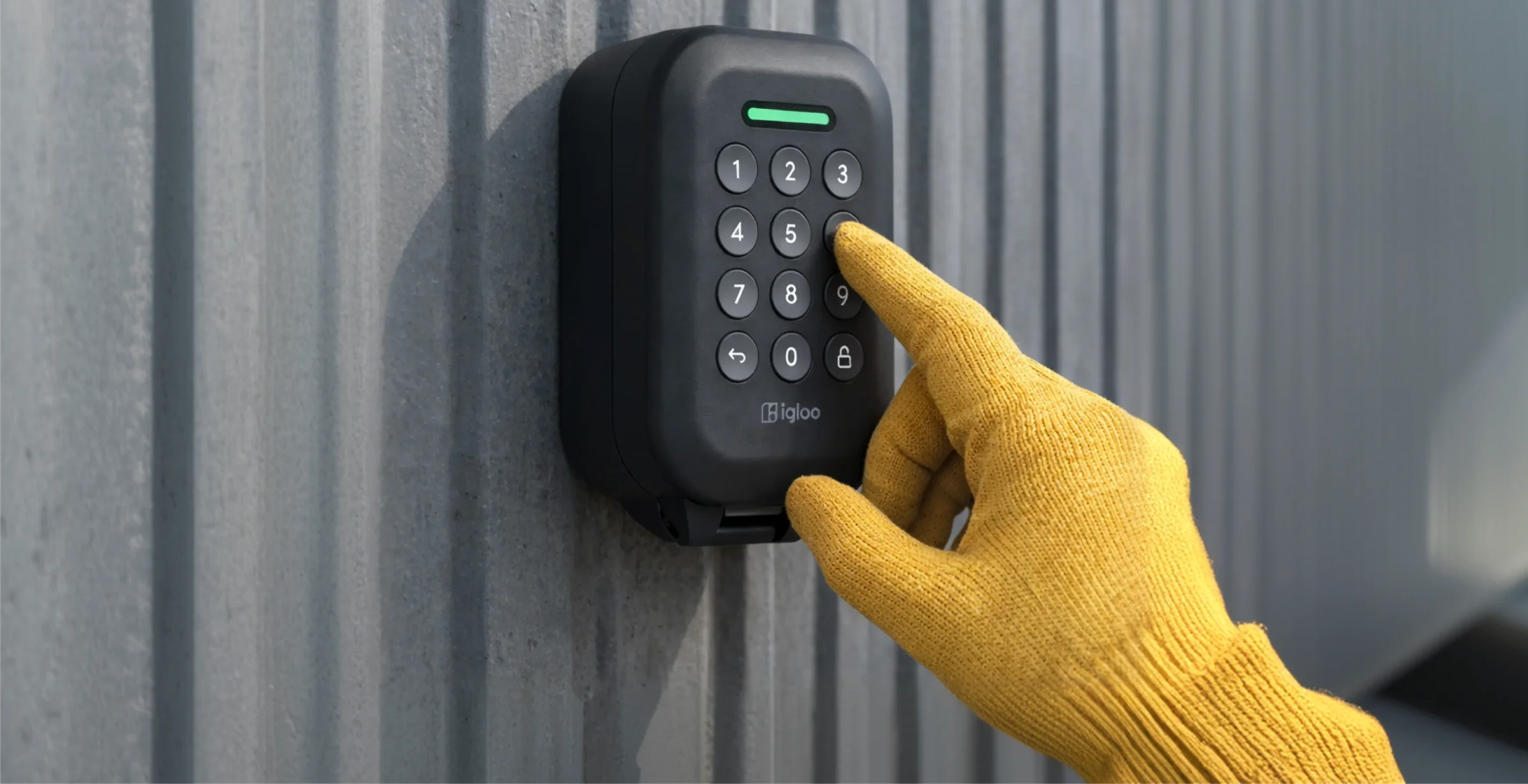 A gloved hand entering a PIN on an igloo Lockbox outdoors, showing its rugged weatherproof build